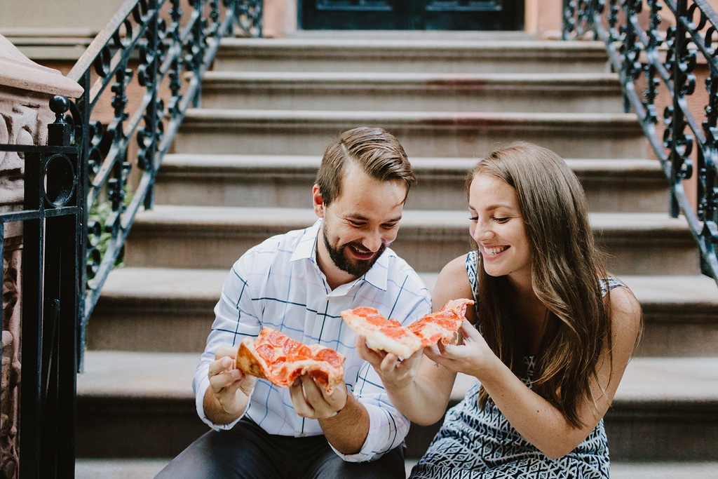 couple eating pizza on a brownstone