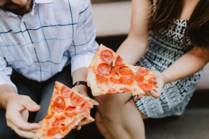 couple eating pizza on a brownstone