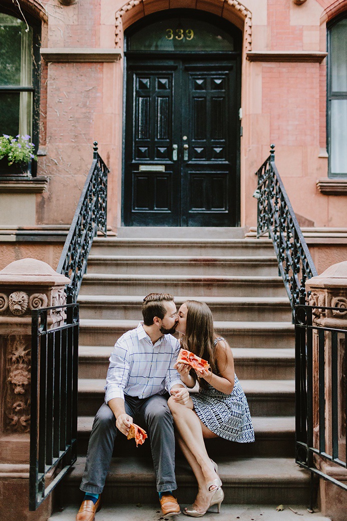 couple eating pizza on a brownstone