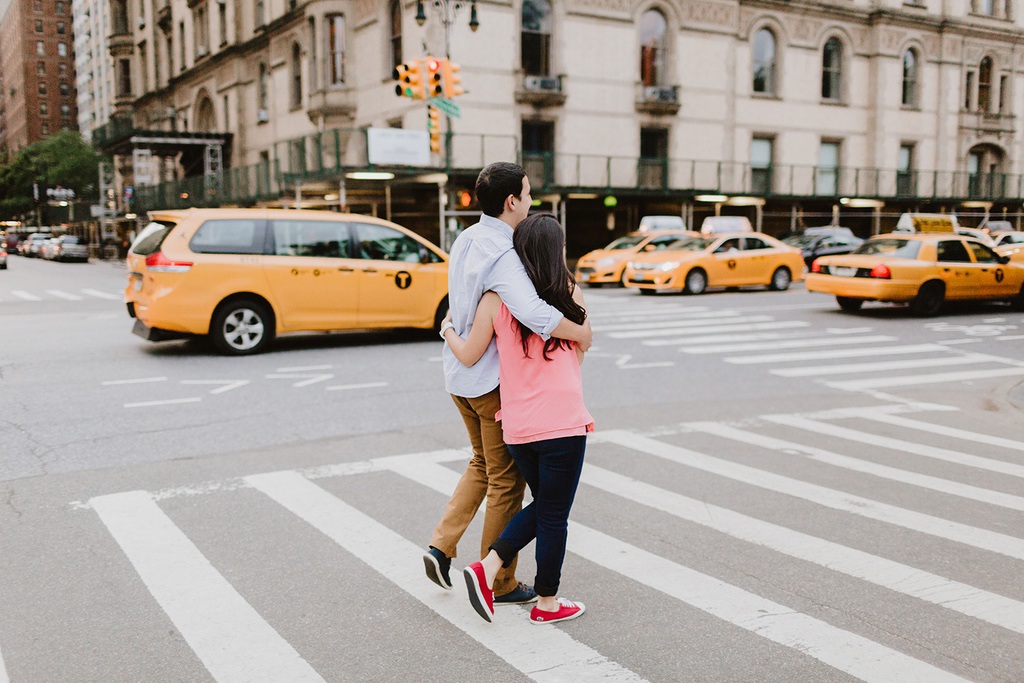 NYC couple holding hands next to a cab