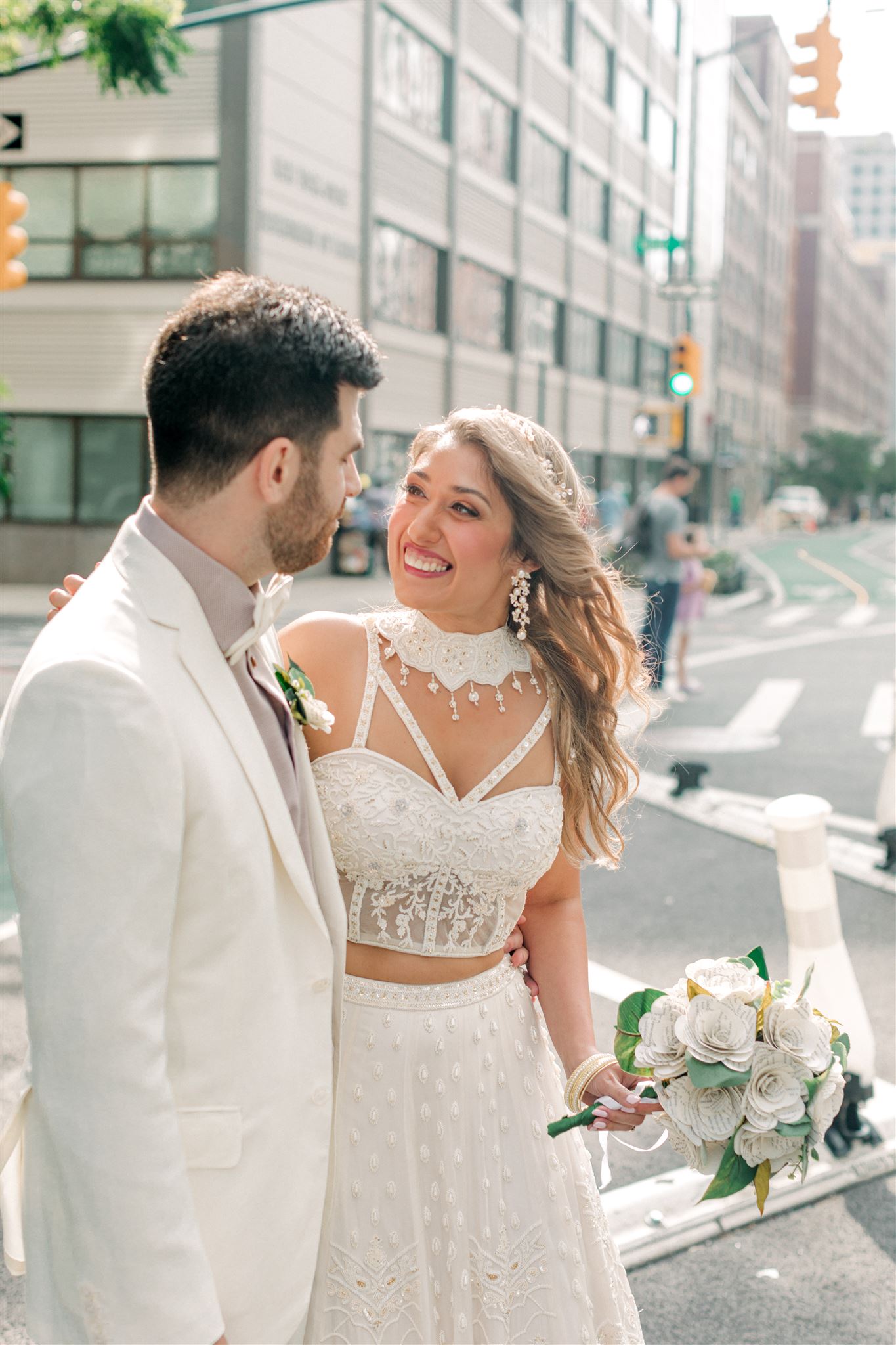 bride and groom on a crosswalk in New York City smiling at each other as they cross the street on their wedding day