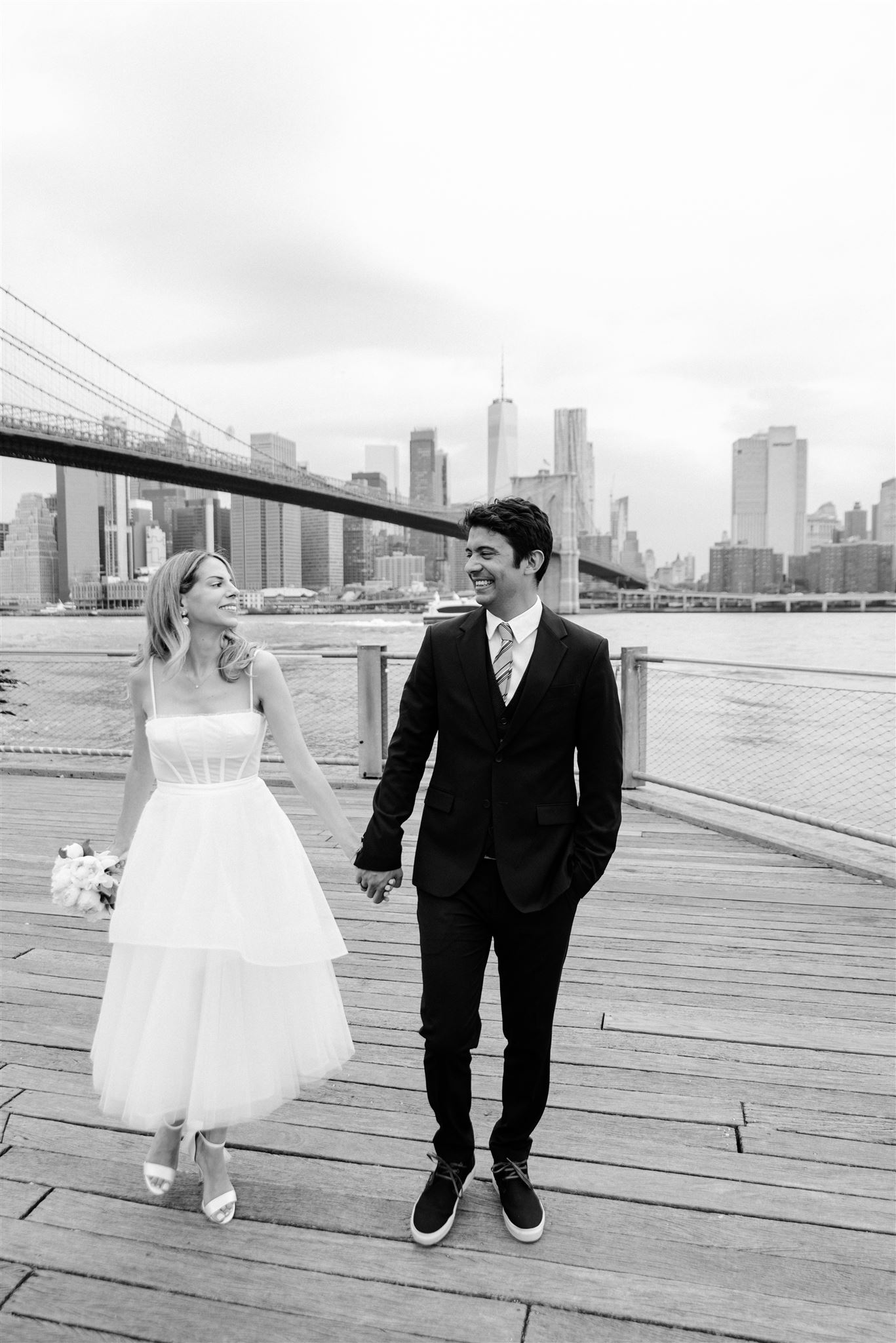 bride and groom smiling at each other as they take couples pictures in front of the NYC skyline 