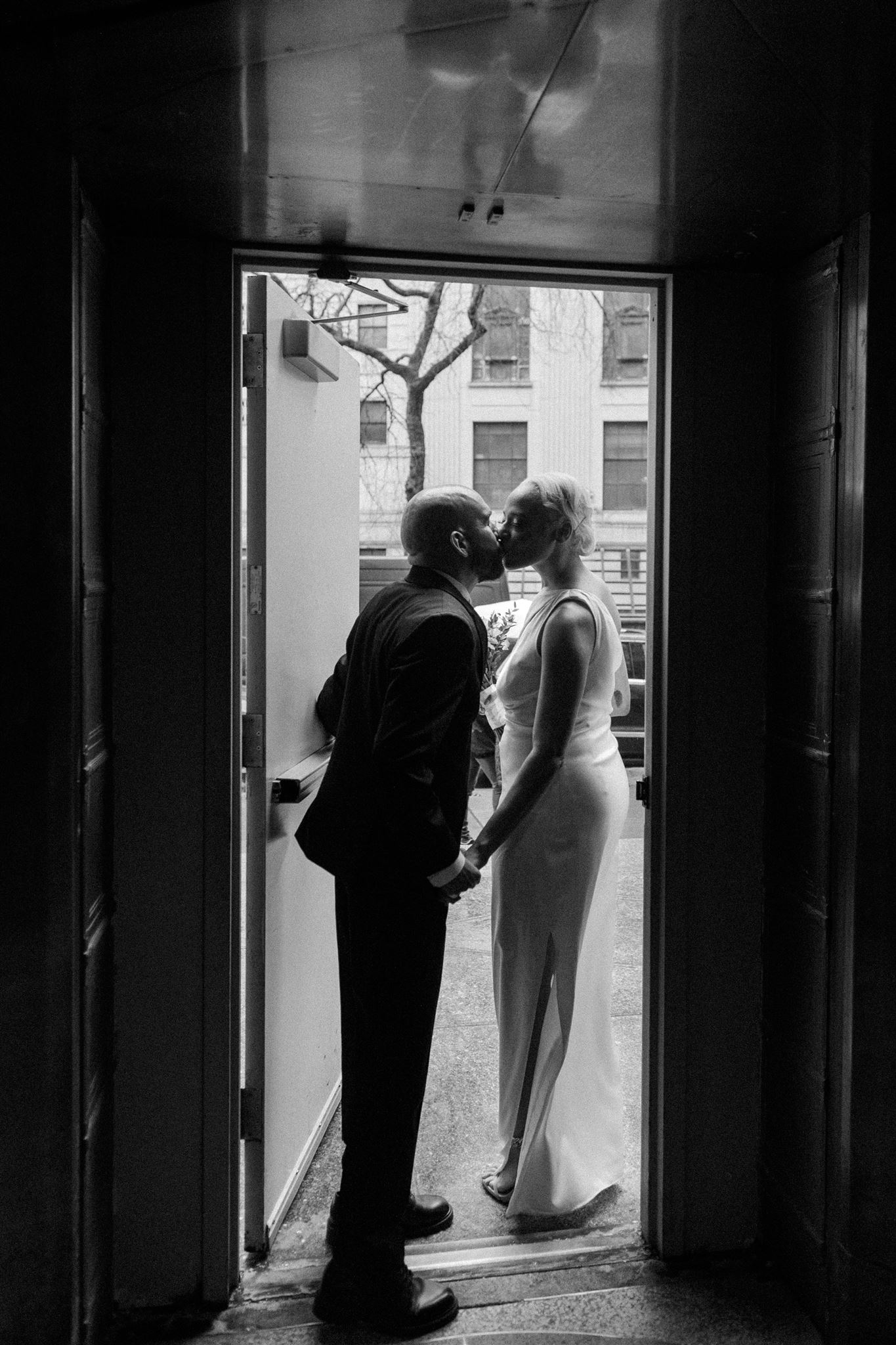 bride and groom leaving NYC city hall kissing