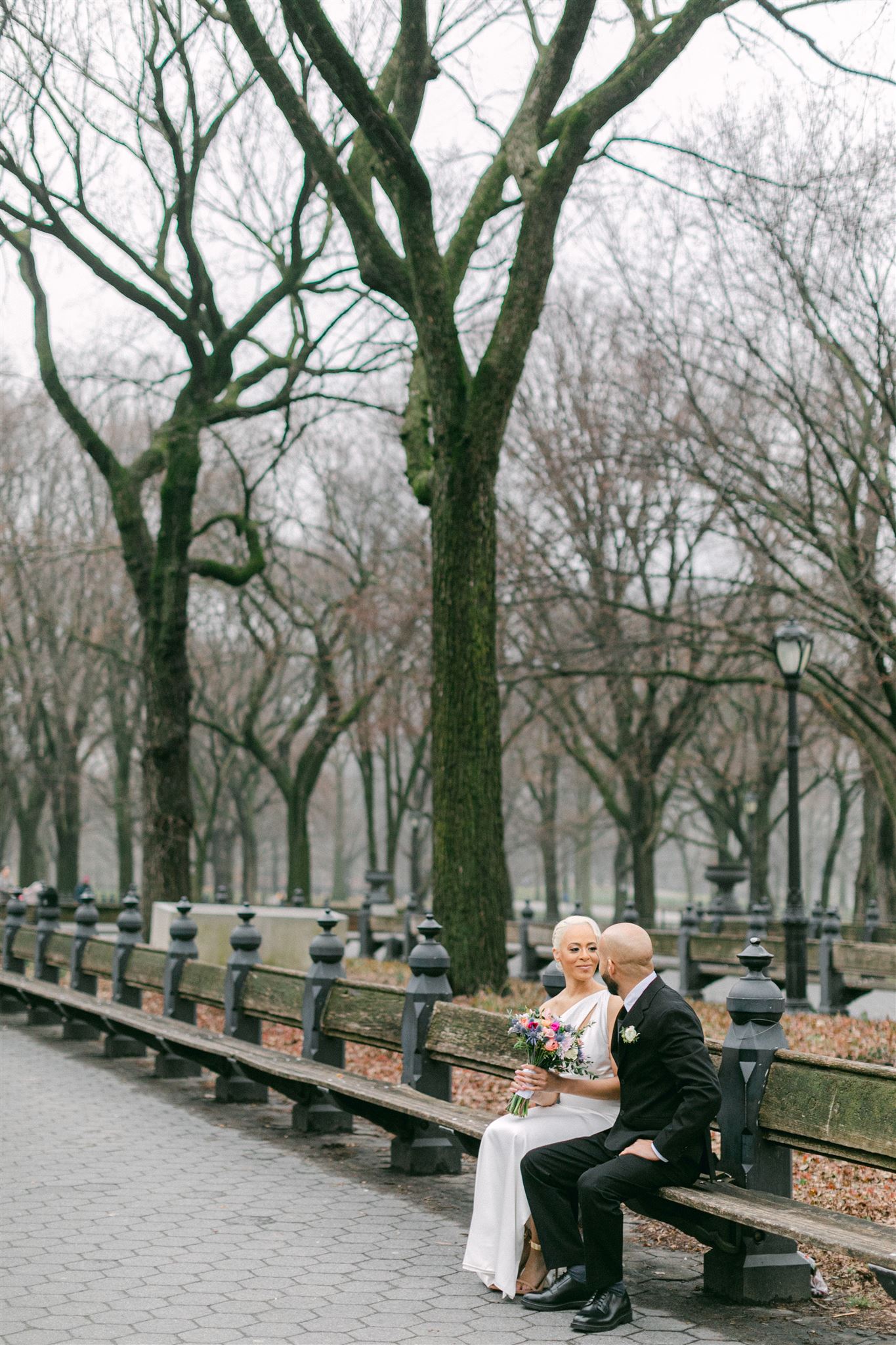 bride and groom sitting on a bench in a park in NYC after getting married at NYC city hall