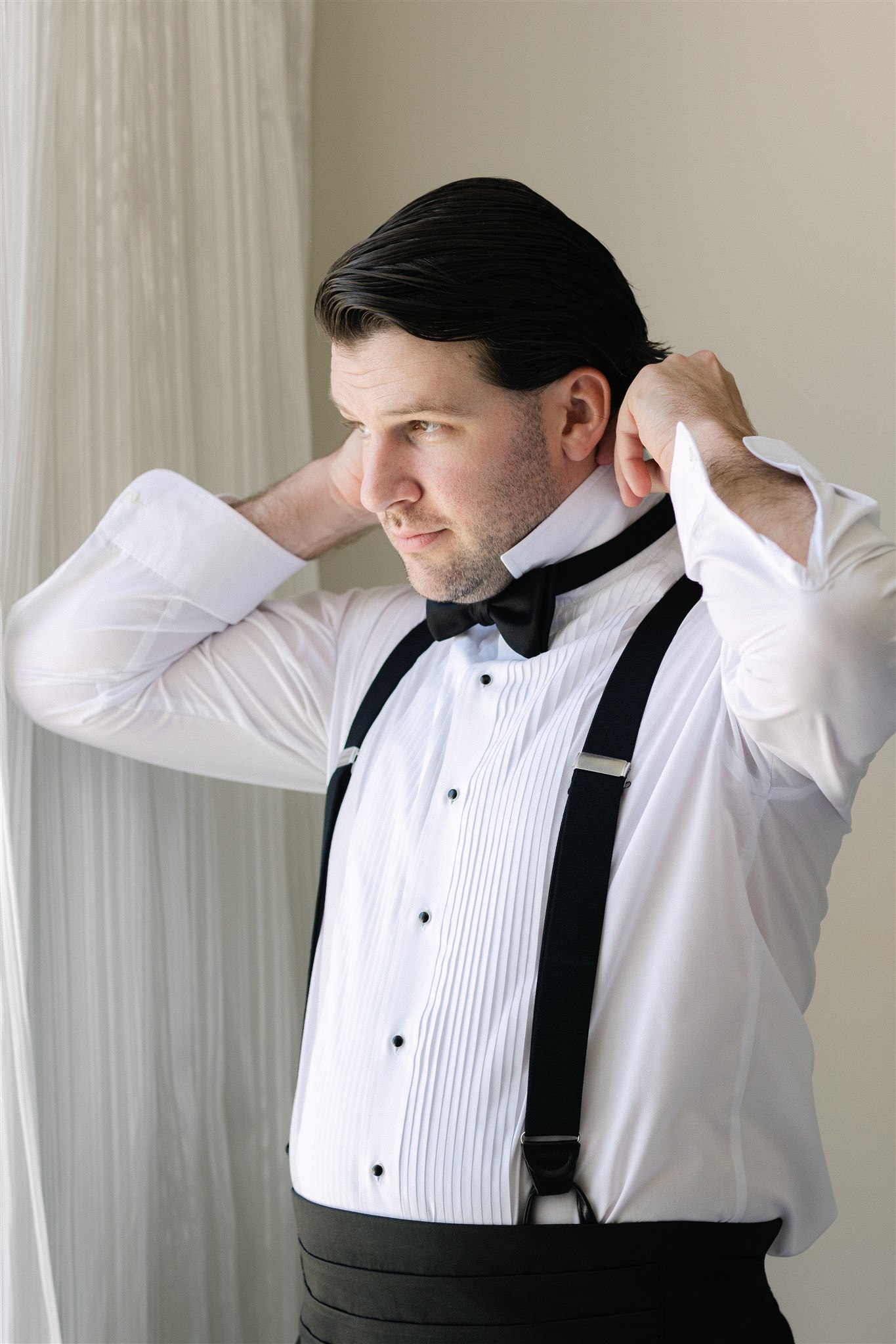 groom getting ready for his wedding day putting on his bow tie