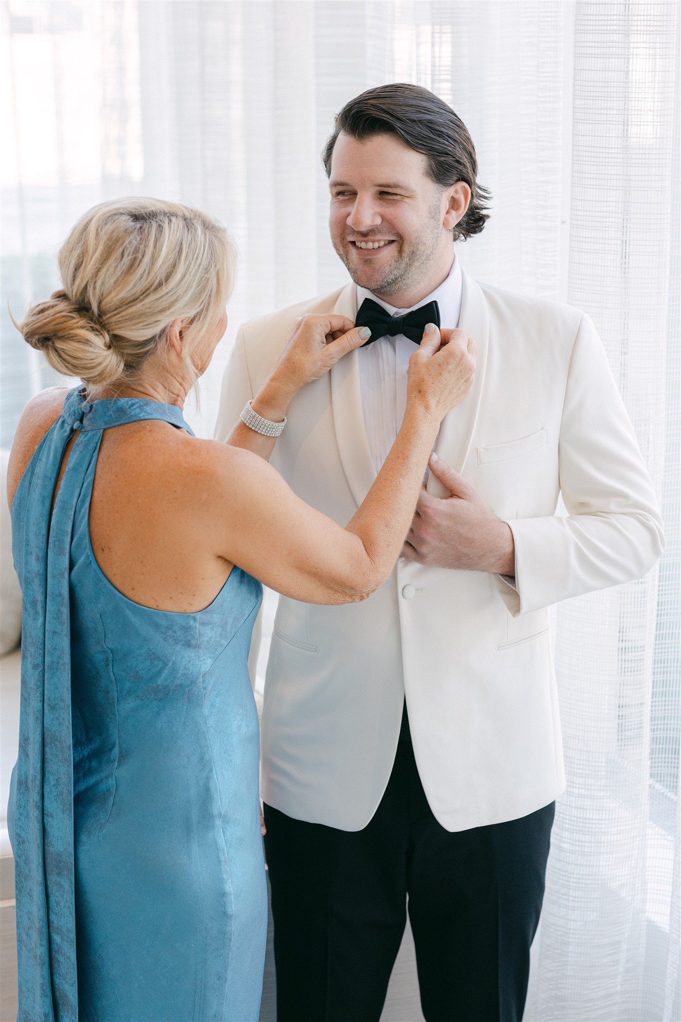 grooms mother adjusting his bow tie