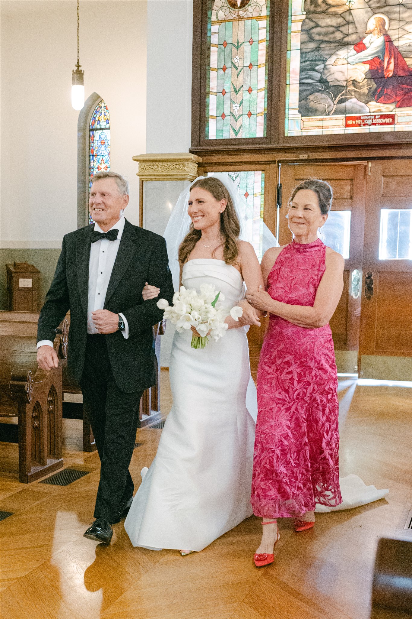 bride walking down the aisle with her mom and dada