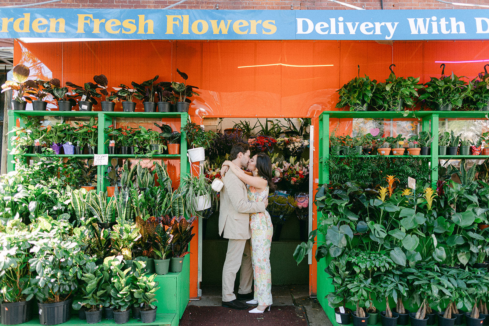 man and a woman kissing outside a flower bodega in NYC