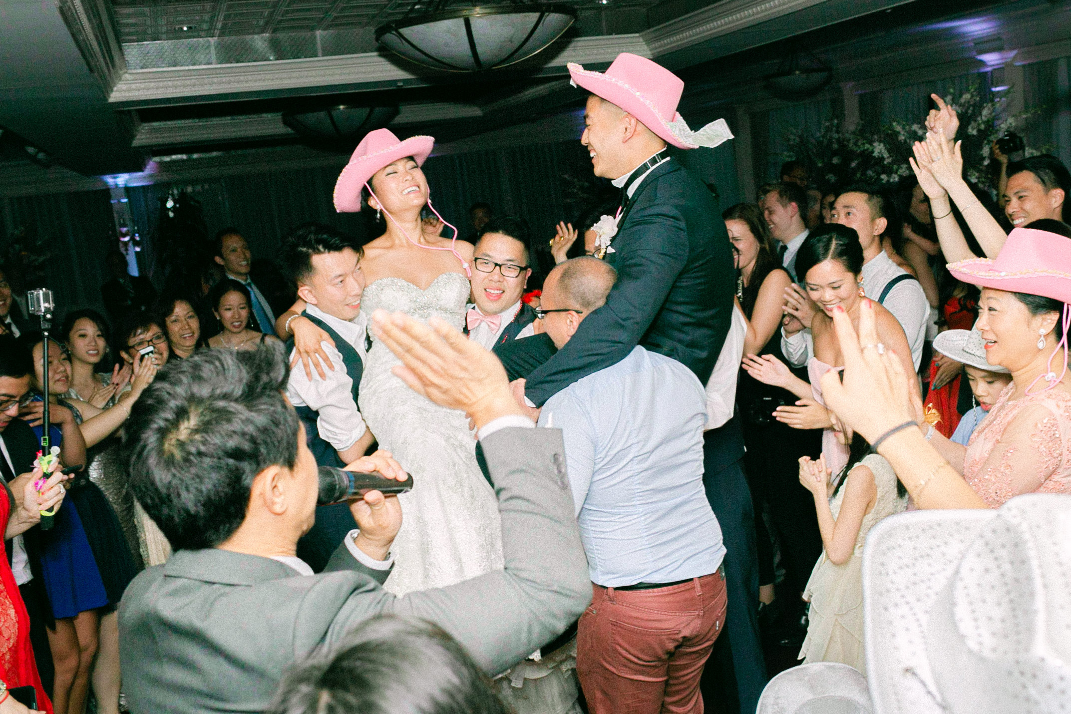 A bride and groom wearing pink cowboy hats during their wedding reception