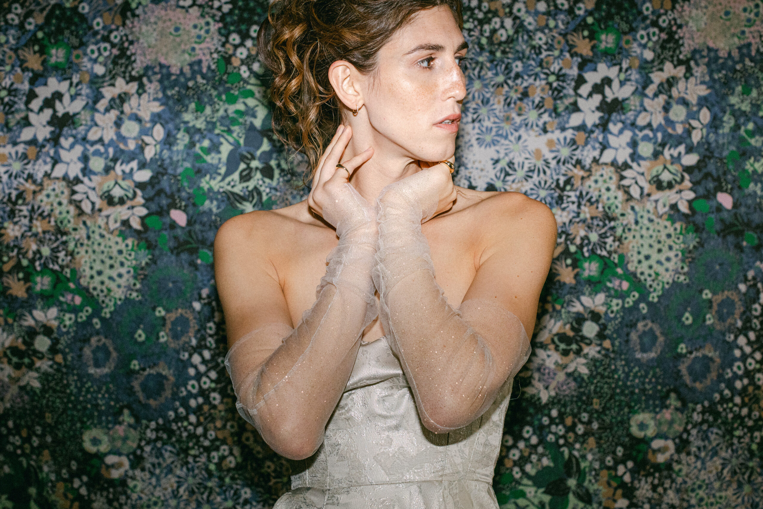 A flash photo of a bride wearing a wedding dress in front of colorful wallpaper