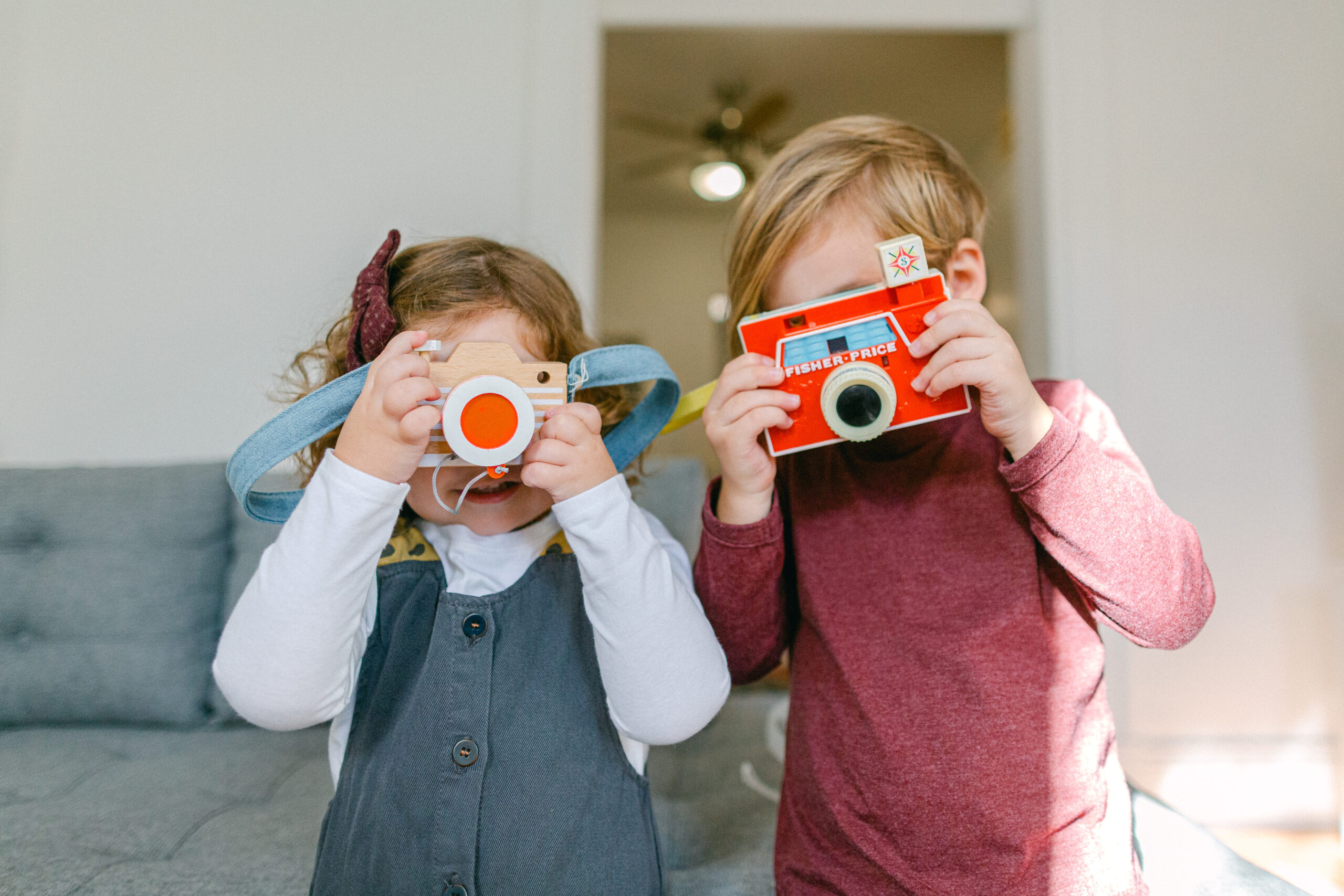 A little boy and little girl holding toy cameras