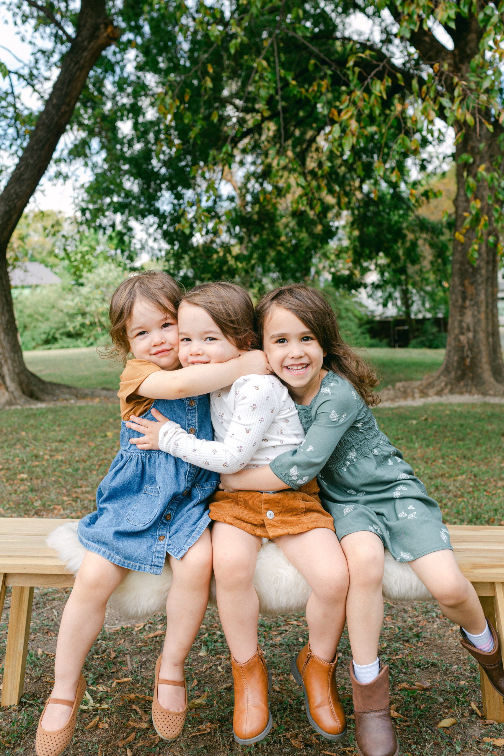 three little girls hugging each other on a beach during a family photography session