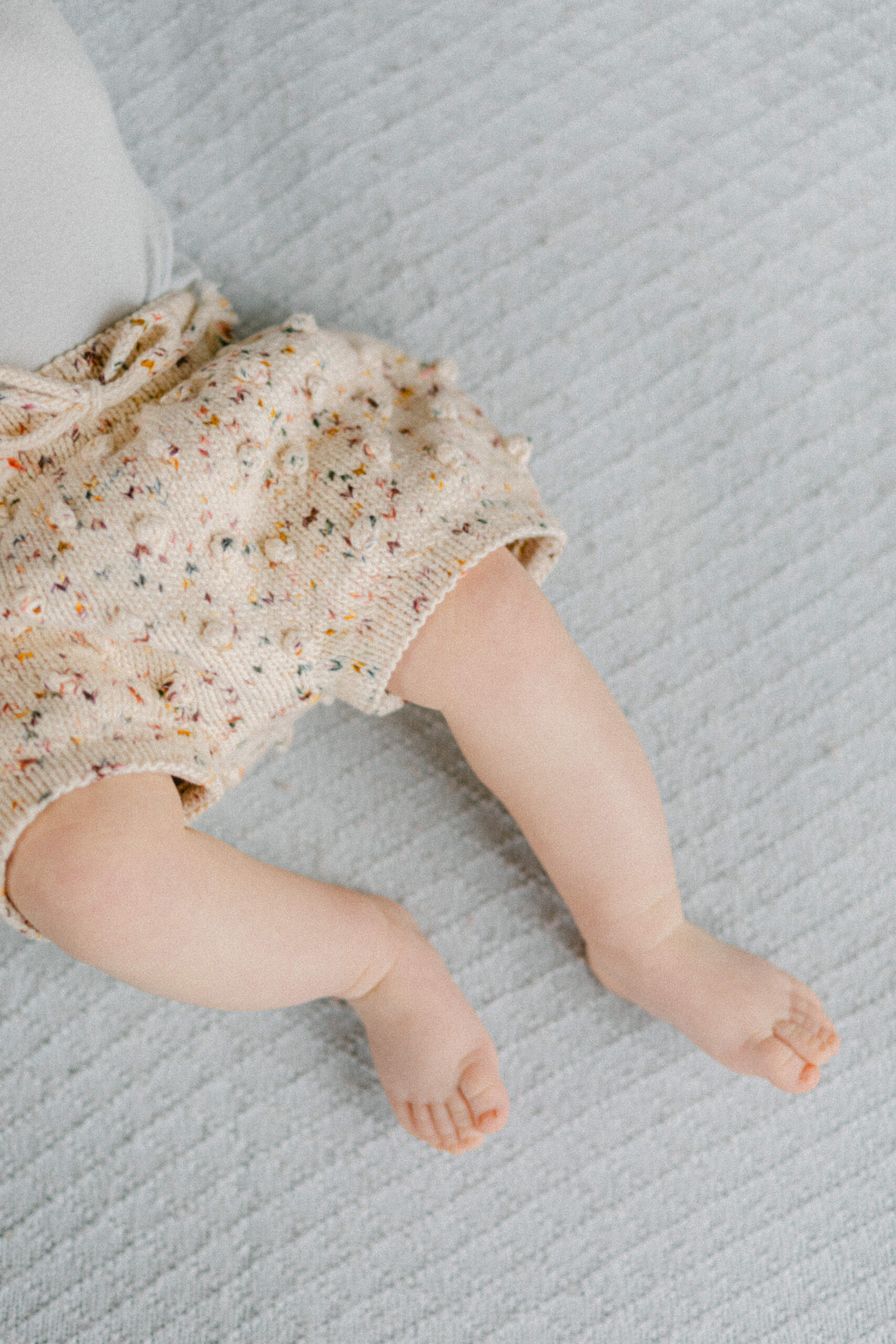 A baby's legs with the baby wearing knit shorts 