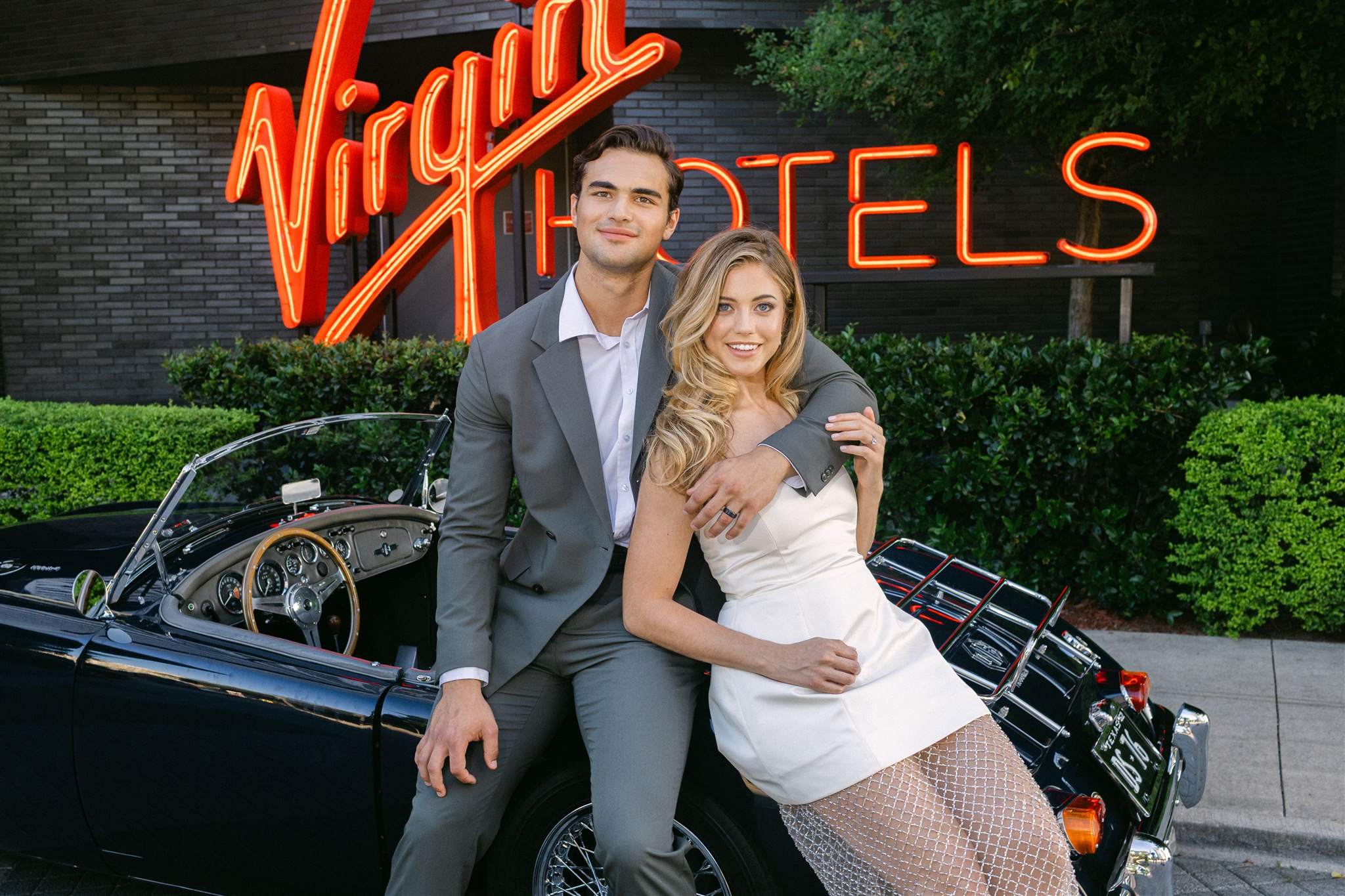Rehearsal dinner at Virgin Hotels Dallas a couple leans against their vintage getaway car