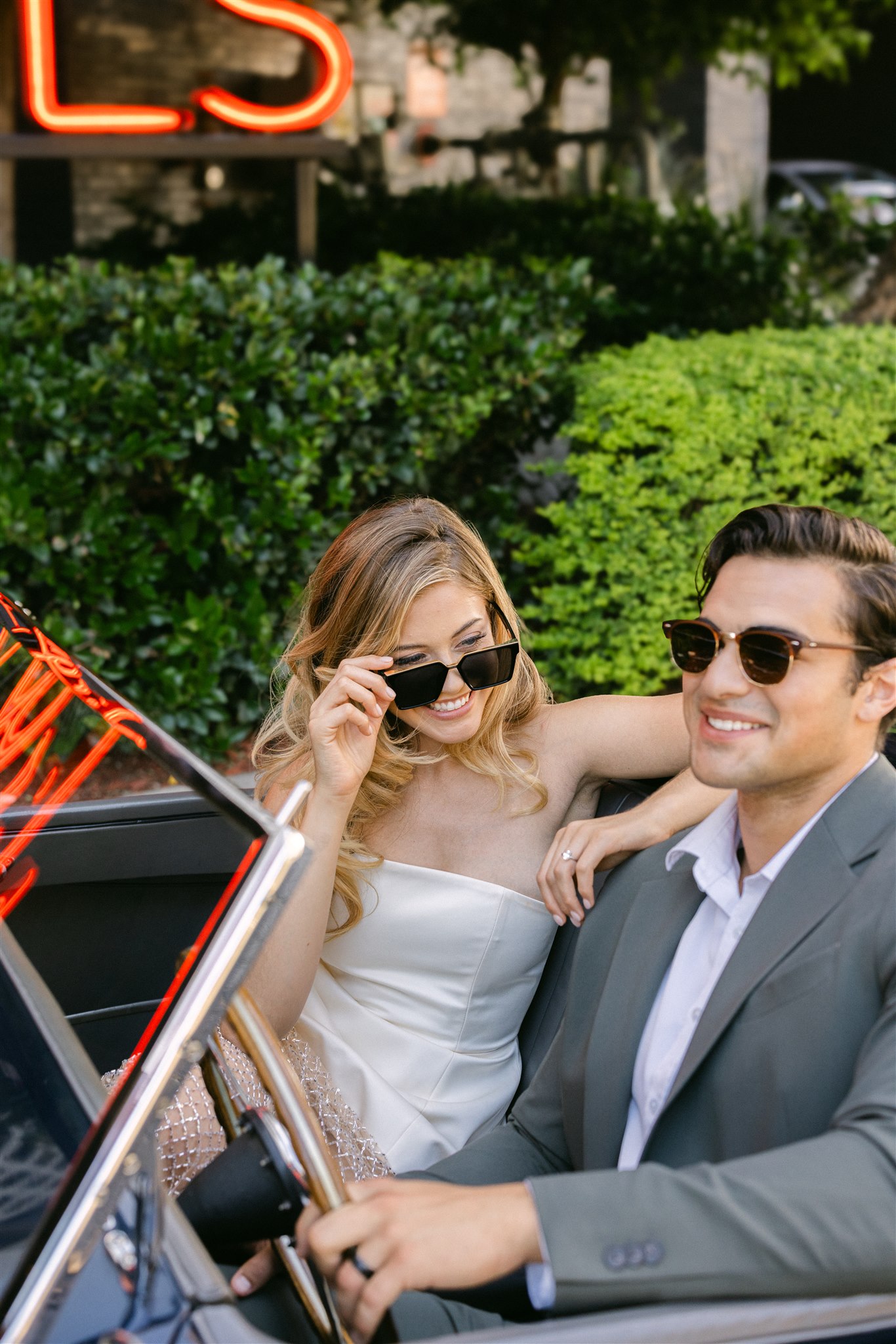 A couple in a vintage getaway car in front of the virgin hotels dallas smiling 