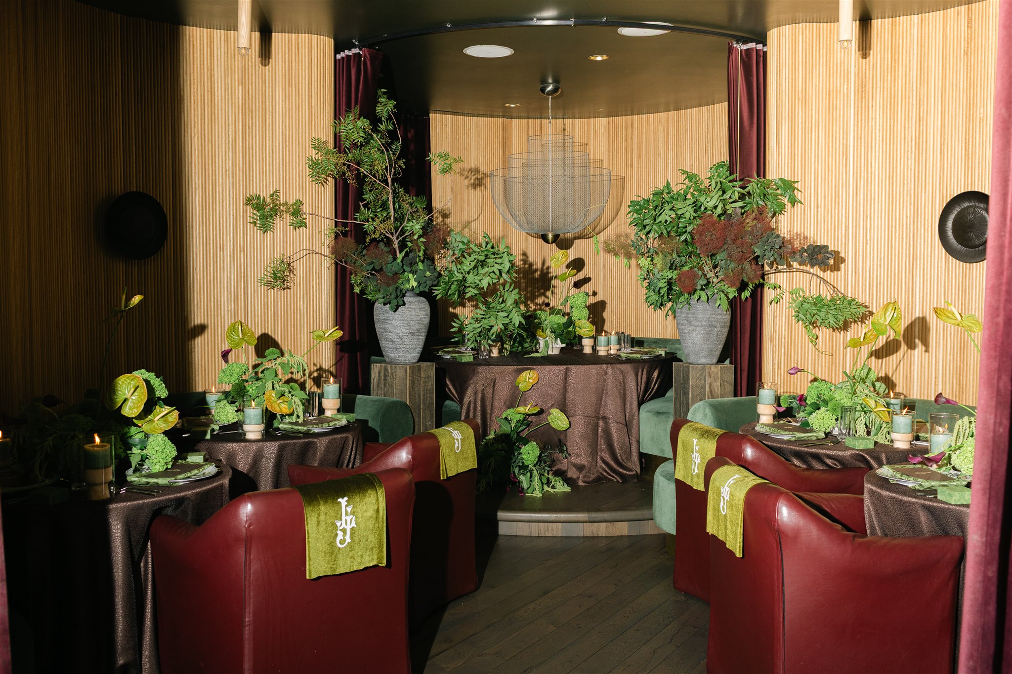 A moody rehearsal dinner at virgin hotels dallas with red chairs, lush green florals and gucci accents