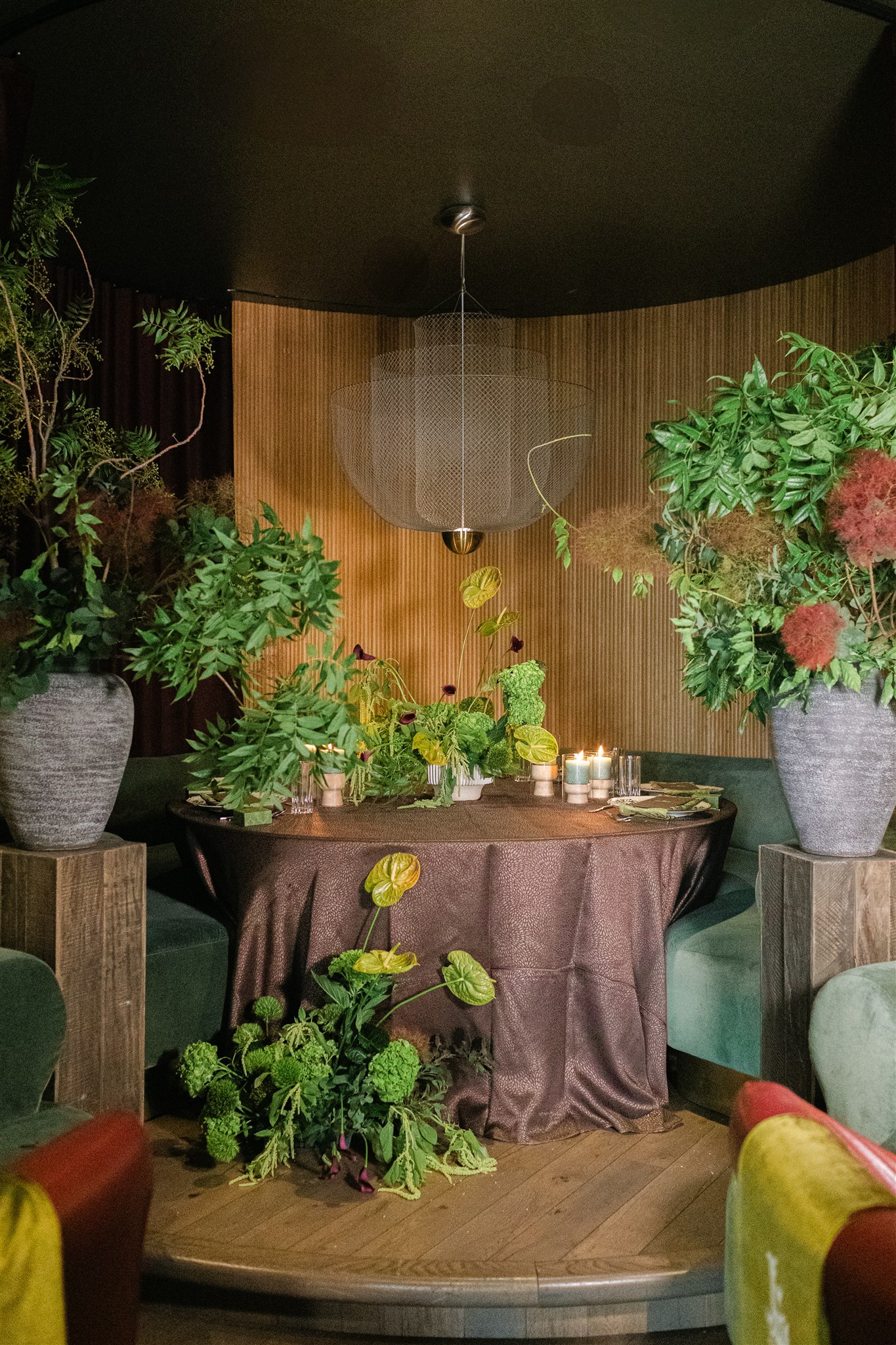 A moody rehearsal dinner at virgin hotels dallas with red chairs, lush green florals and gucci accents