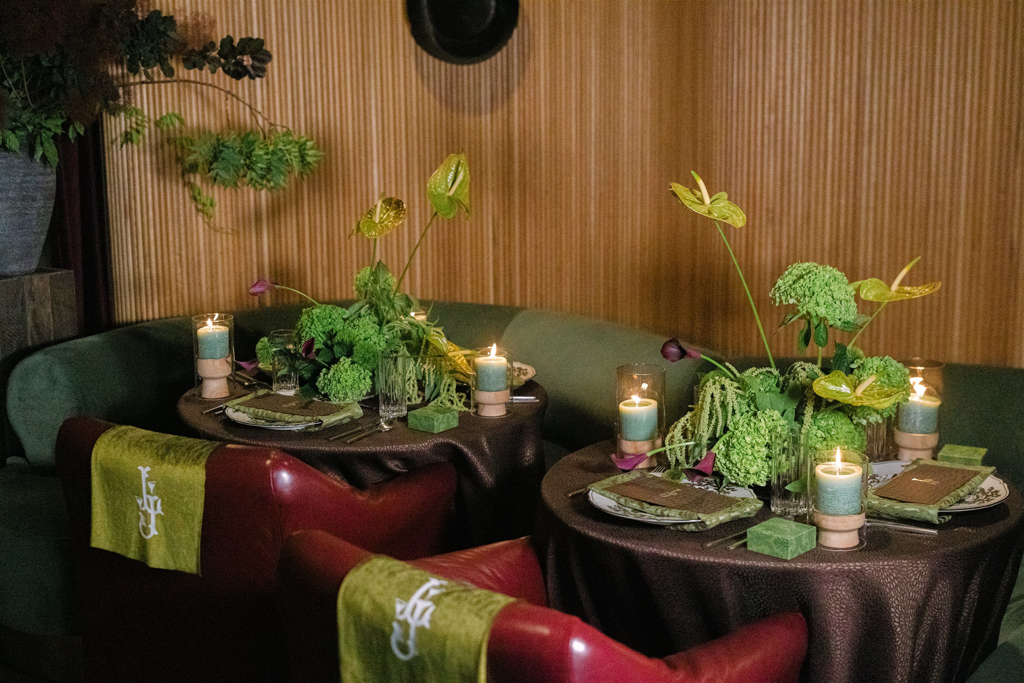 A moody rehearsal dinner at virgin hotels dallas with red chairs, lush green florals and gucci accents