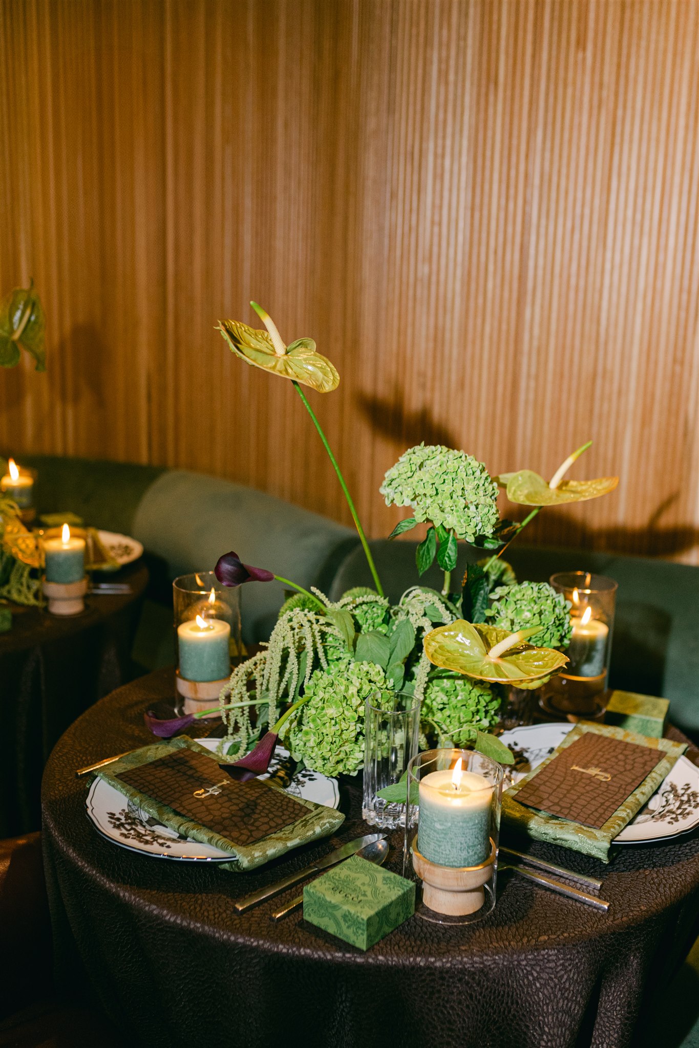 A moody rehearsal dinner at virgin hotels dallas with red chairs, lush green florals and gucci accents