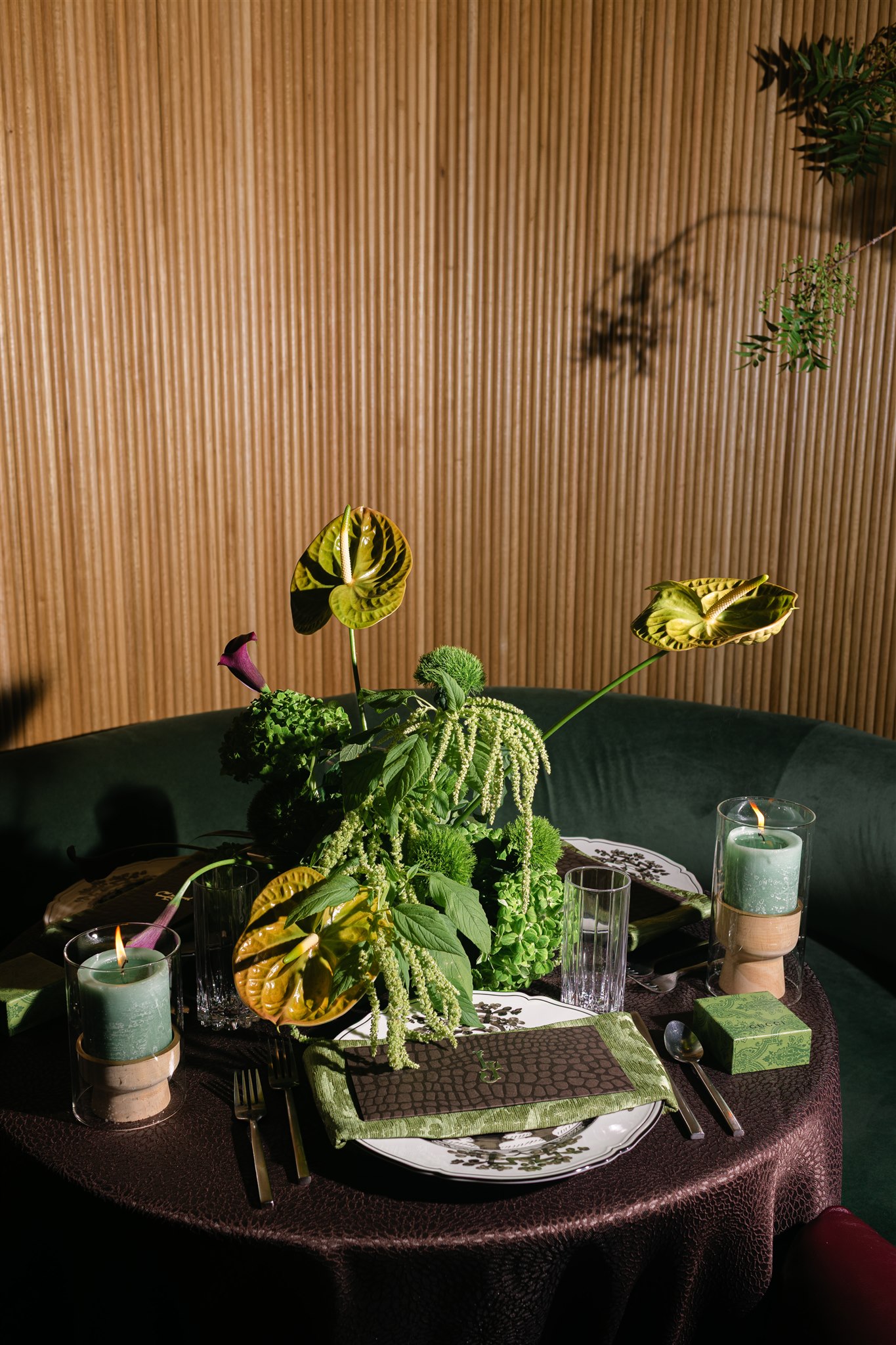 A moody rehearsal dinner at virgin hotels dallas with red chairs, lush green florals and gucci accents