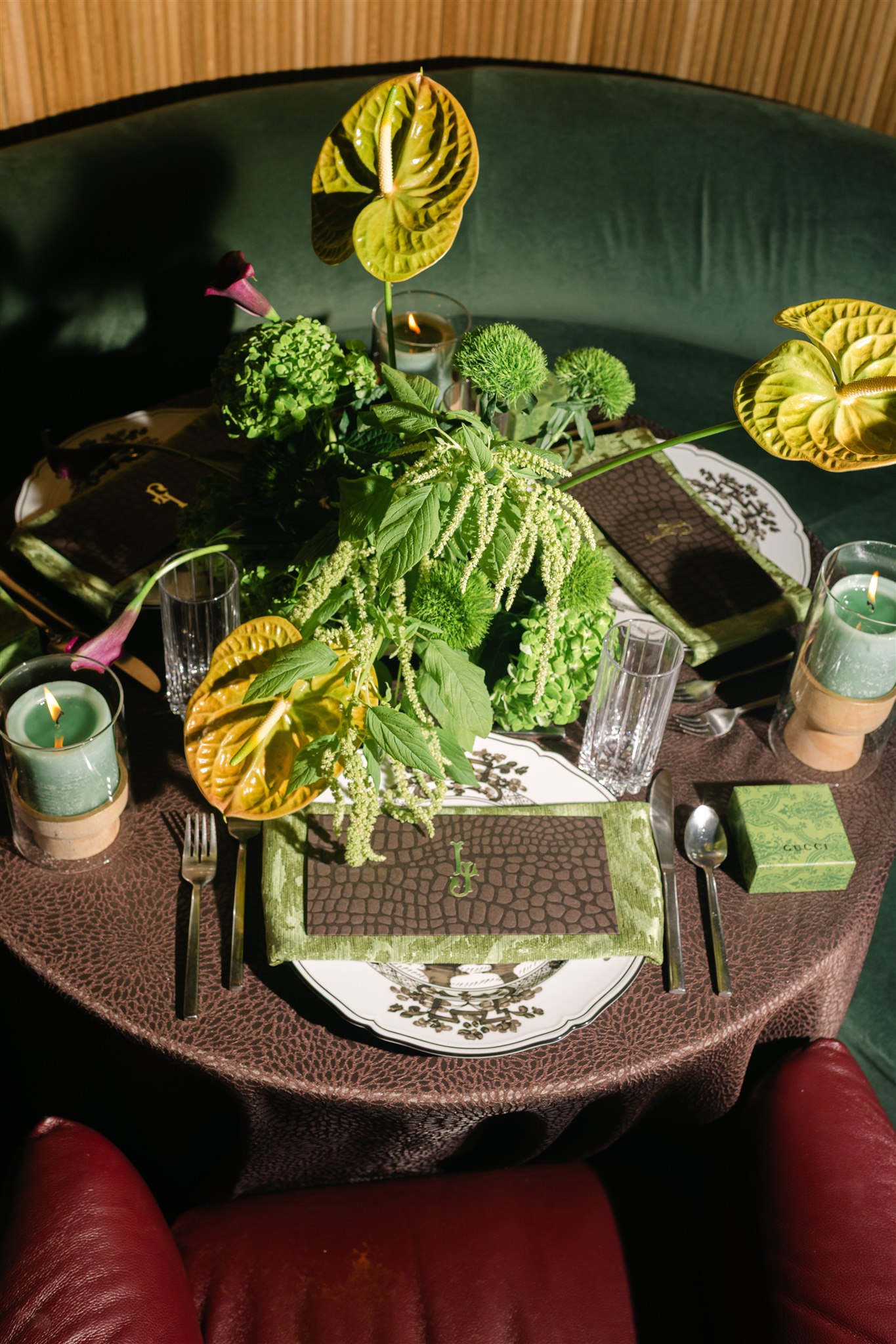 A moody rehearsal dinner at virgin hotels dallas with red chairs, lush green florals and gucci accents