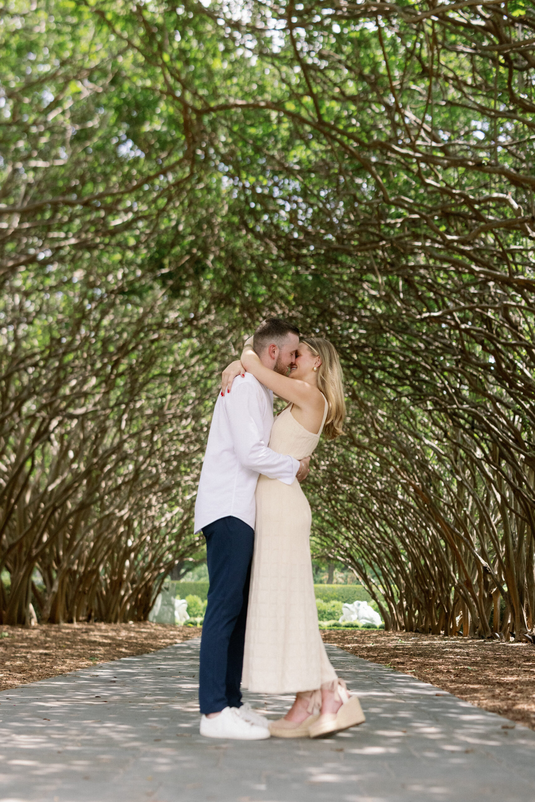 a man and woman kissing at the dallas arboretum
