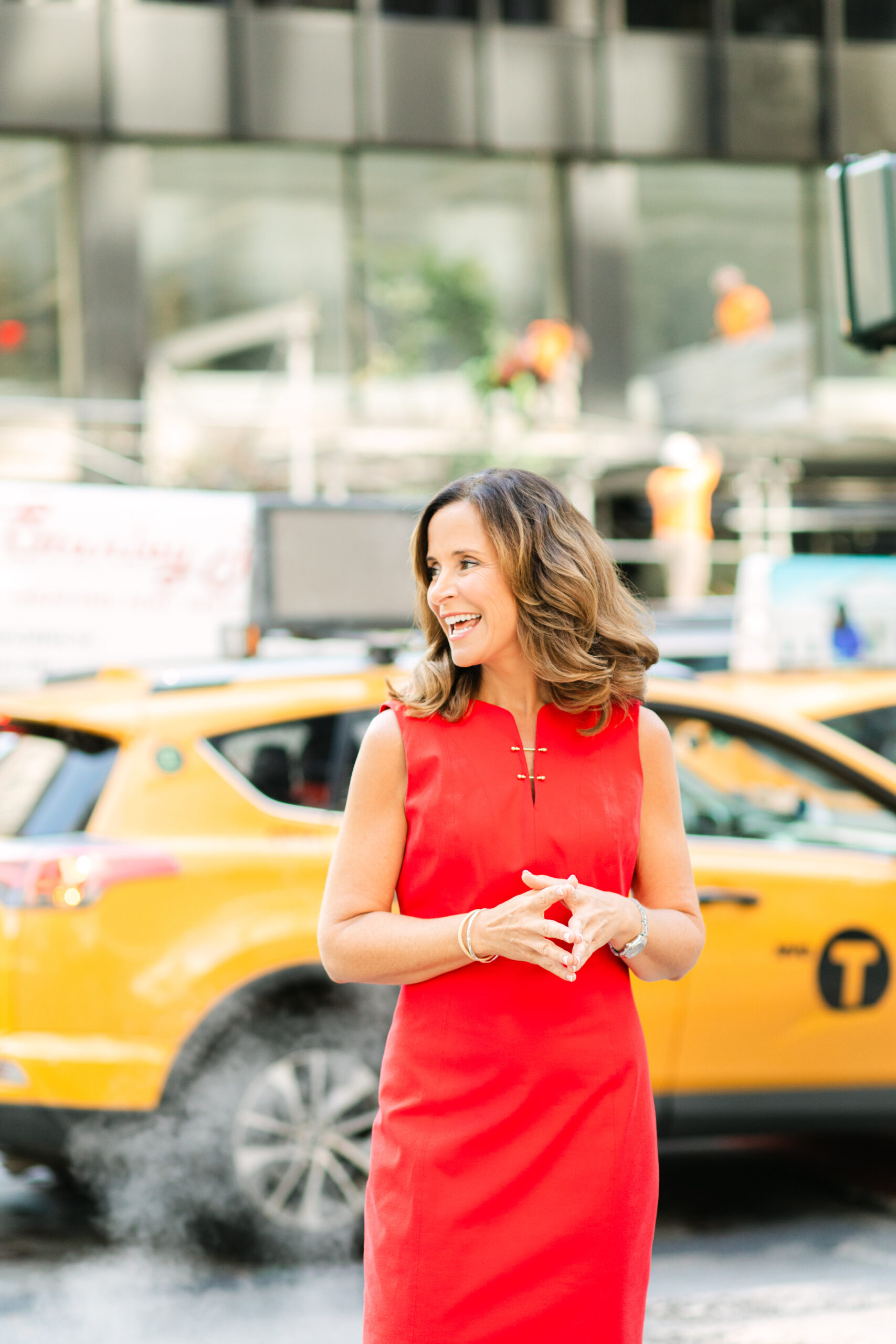 a woman in a red dress on the sidewalk on NYC in front of a taxi