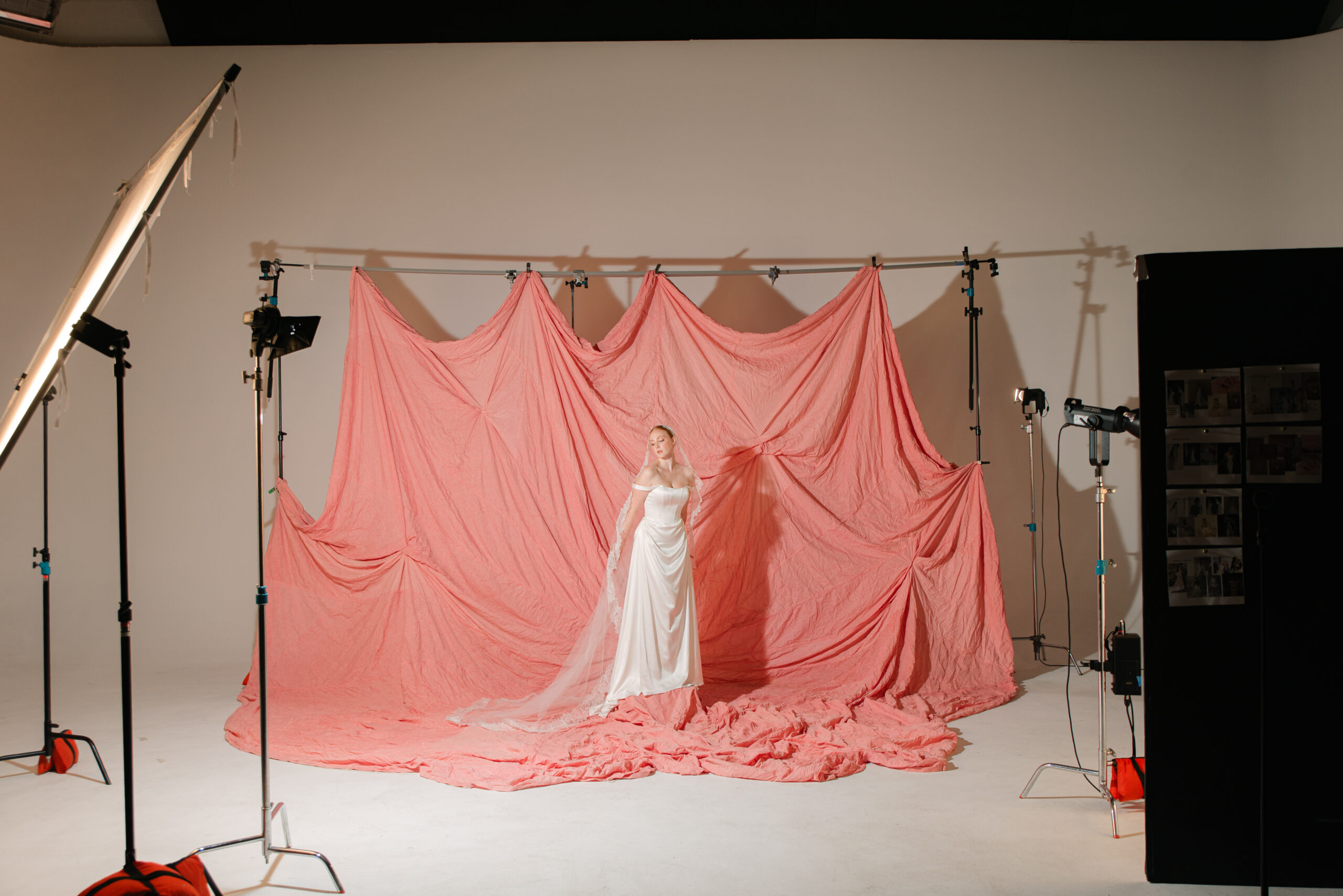 A production set of a bridal branding photography session in NYC the bride is in front of a peachy pink backdrop