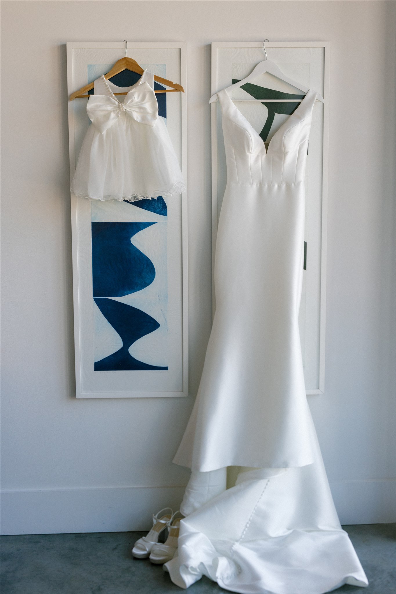 a wedding dress hanging up next to a flower girl dress