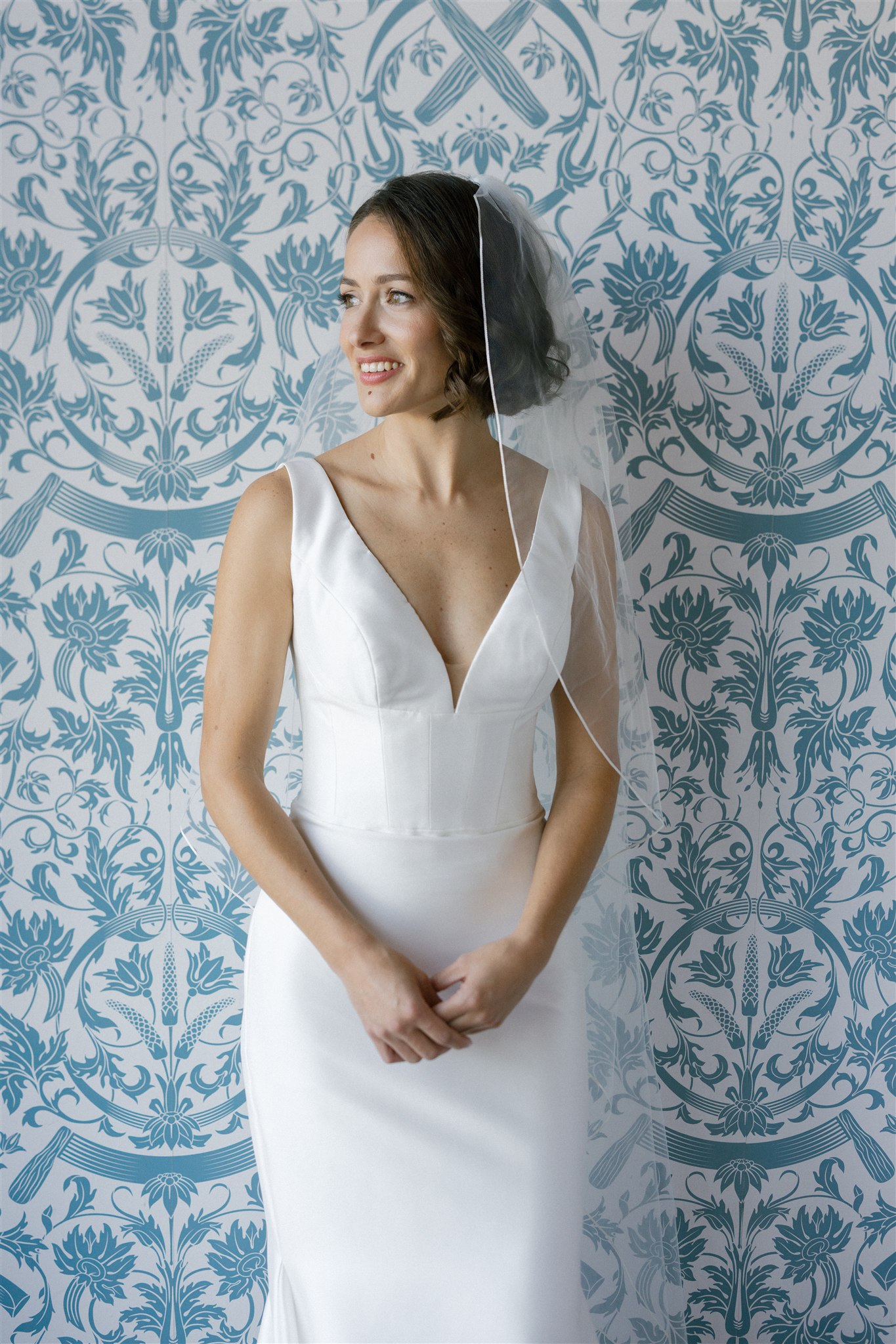 a bride standing in front of a blue and white wallpapered wall