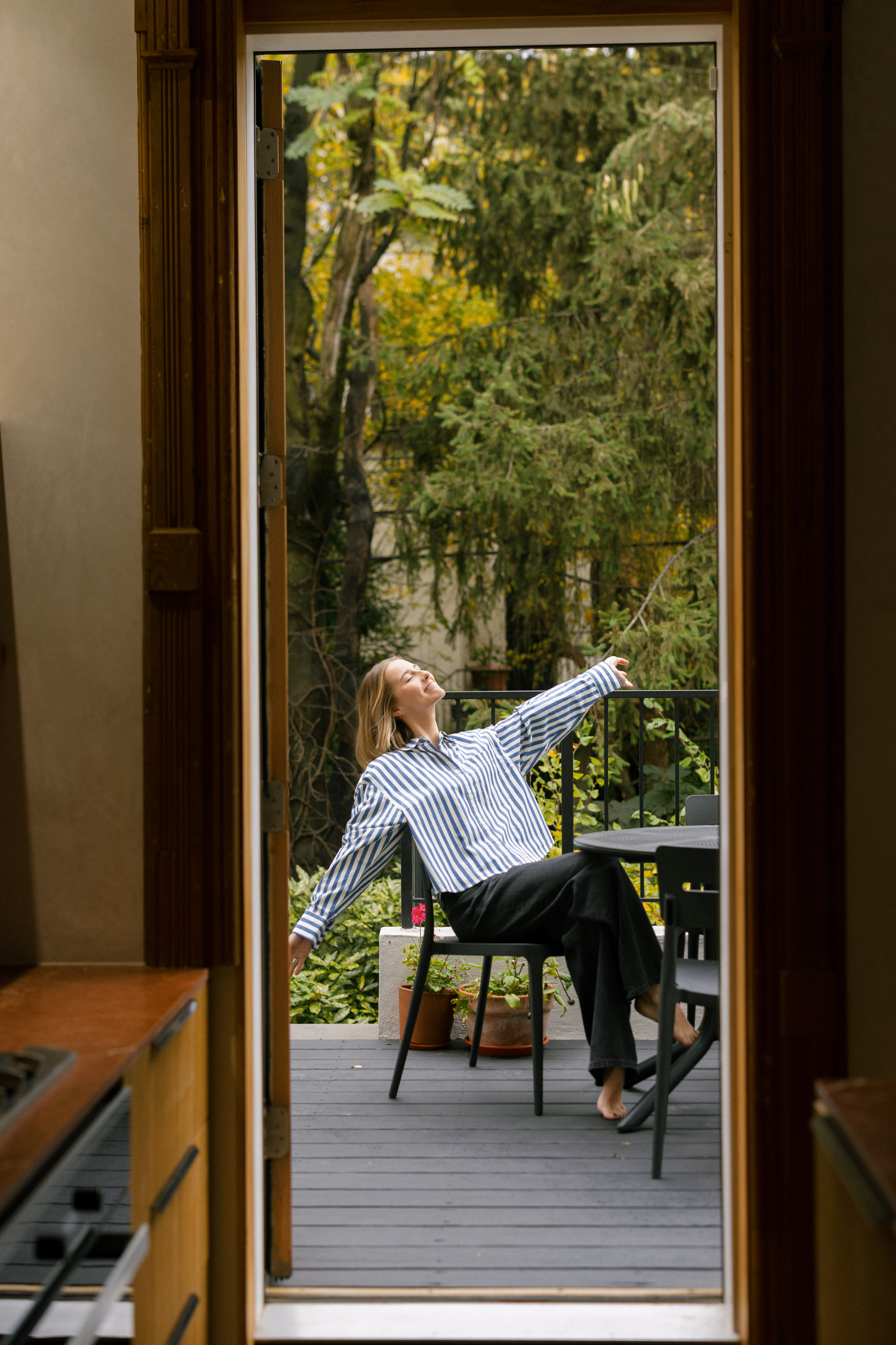 a girl sitting outside on a patio smiling in NYC for her brand photos