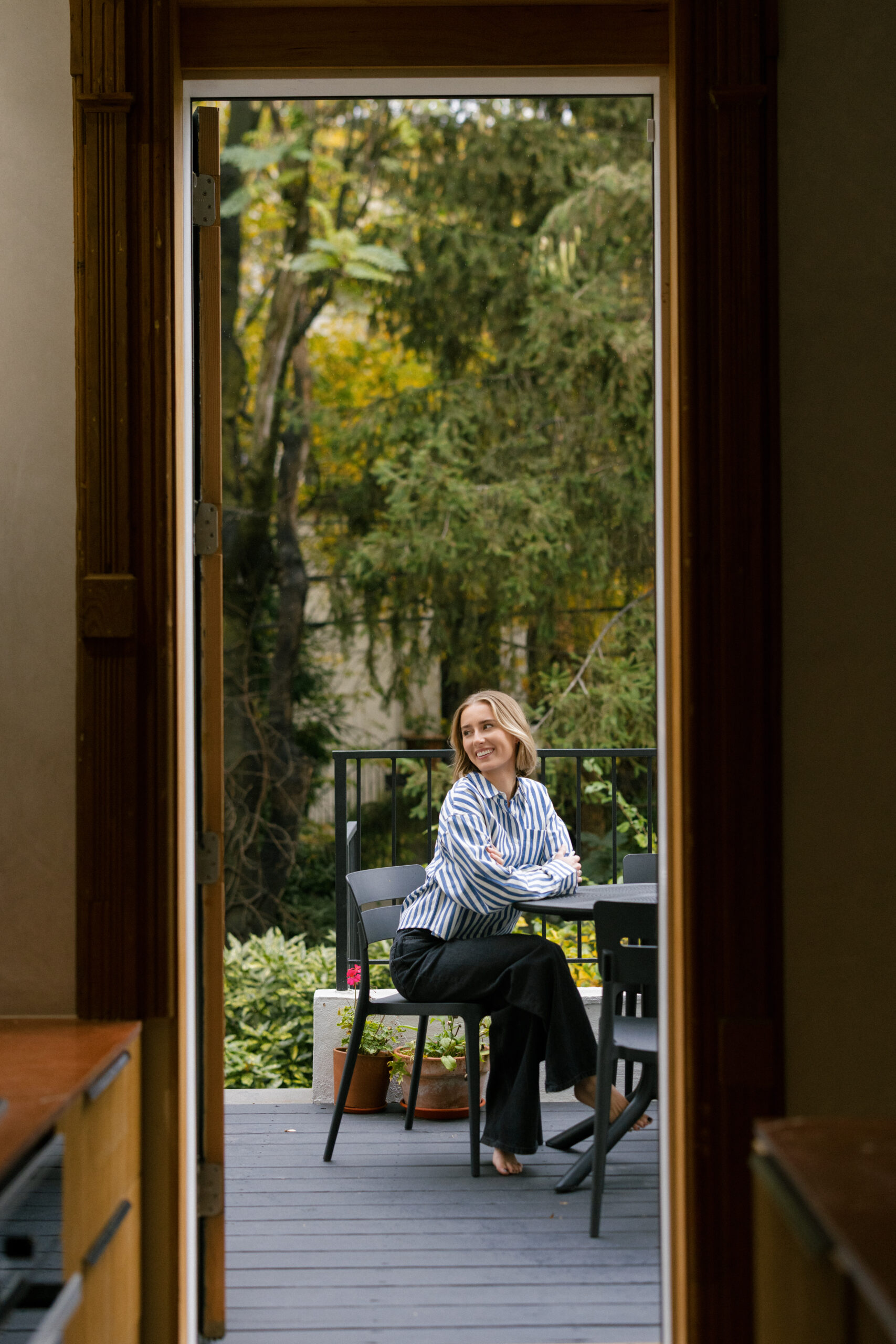 a girl sitting outside on a patio smiling in NYC for her brand photos