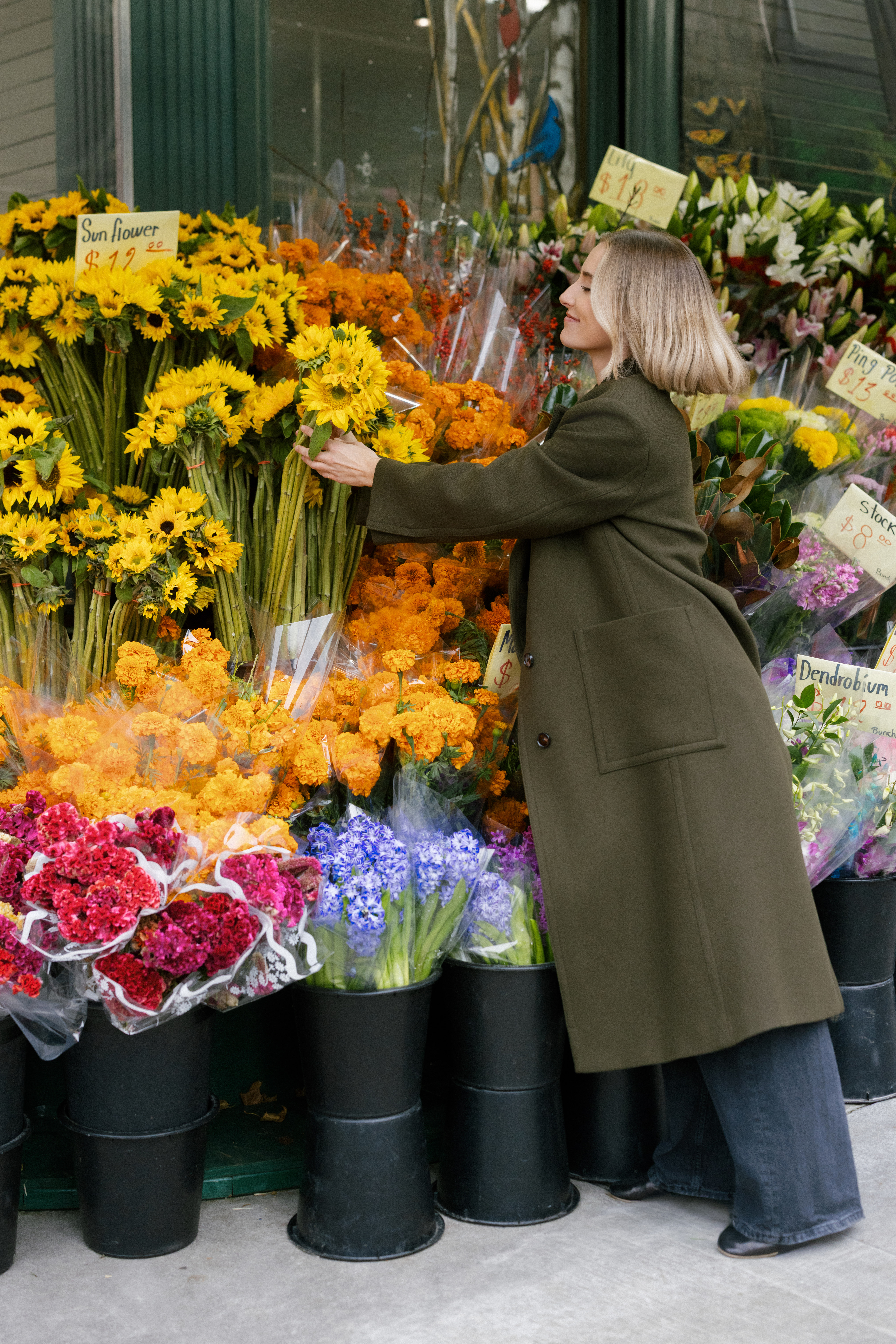 a girl picking out sunflowers at a market in nyc for her brand photos